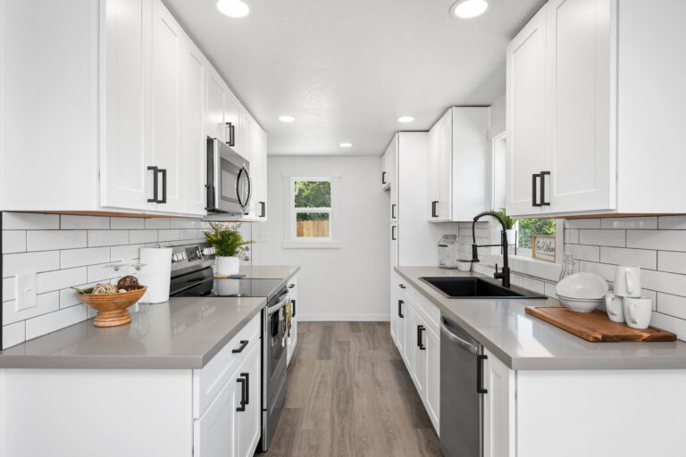 Modern white kitchen with sleek cabinetry, stainless steel appliances, and stylish subway tile backsplash.