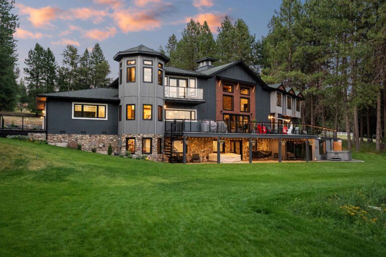 Luxury modern home with stunning architecture, large windows, and scenic green landscape at sunset.